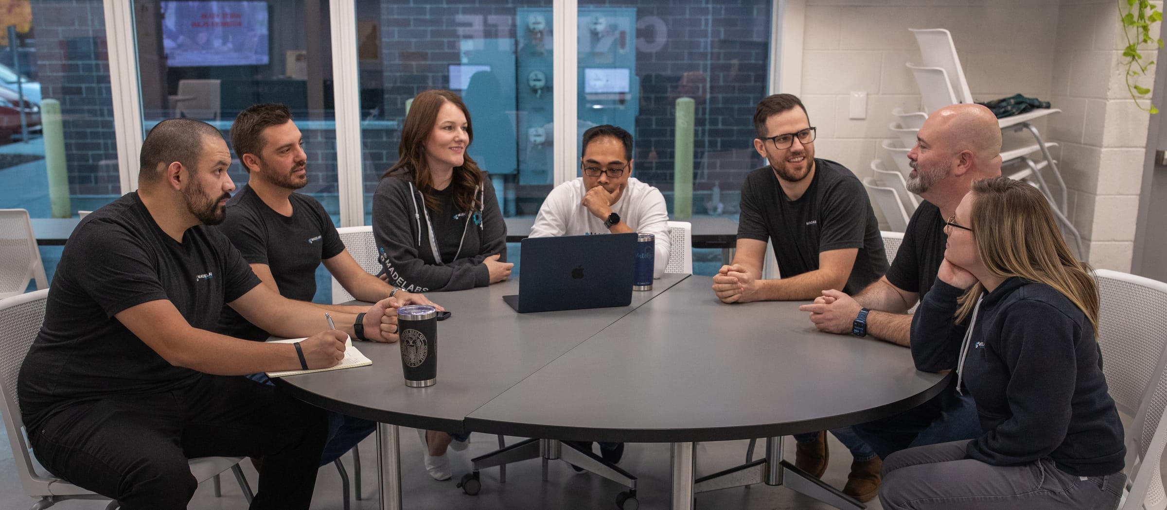 The MadeLabs team of eight around a round table in a bright office with tall windows